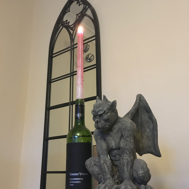 A dripping candle from Yankee Candle, with a gargoyle (grotesque), in front of a gothic-style mirror